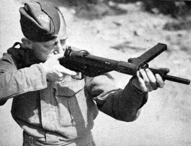 Sort-hvidt foto af soldat, der sigter med en Sten-maskinpistol
