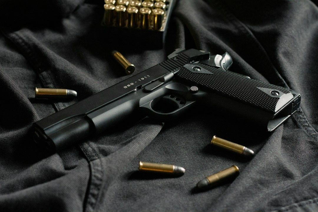 Sort M1911-lignende pistol omgivet af løse patroner på mørkt stof